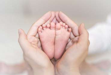 Close up of newborn baby feet on female hands